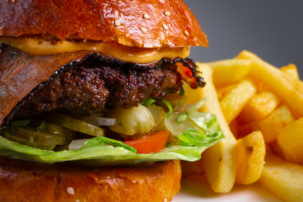 Detail šťavnatého burgeru s hranolkami – profesionální food fotografie pro restauraci The House Restaurant & Pub.